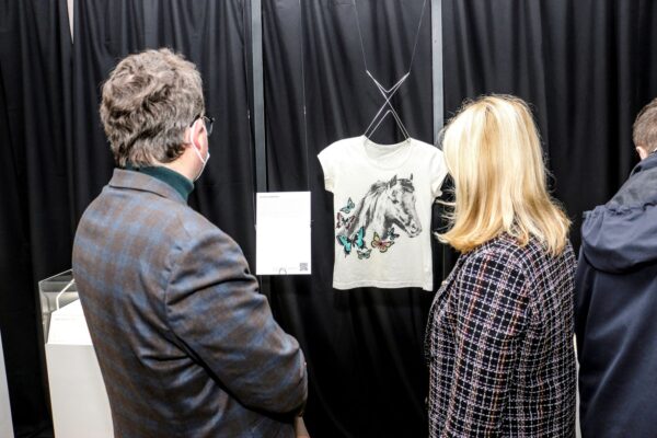Posjetioci u obilasku izložbe u Hersonu, u fokusu je bijela majica kratkih rukava sa slikom konja