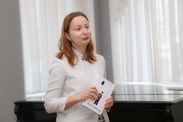 WCM Ukraine's Director holds War Childhood book and addresses those present